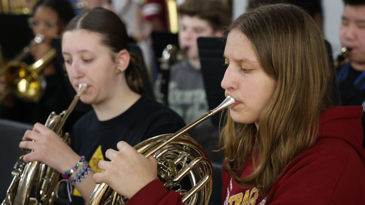 two female students play the french horn 